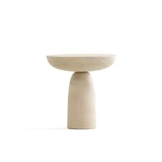 a small white bowl sitting on top of a cement pedestal with one leg raised up