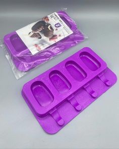 two purple ice trays sitting next to each other on top of a gray table