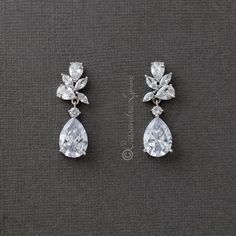 two pairs of diamond earrings on a gray surface