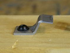 a metal object sitting on top of a wooden table next to a black ball and screw