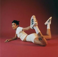 a woman laying on the ground with her legs spread out and wearing white tennis shoes