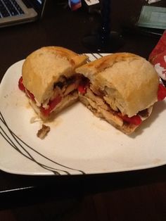 a cut in half sandwich sitting on top of a white plate next to a laptop