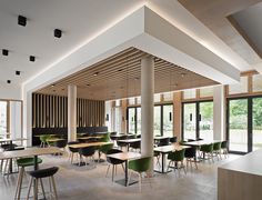 an empty restaurant with green chairs and tables