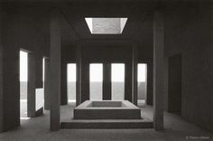 an empty room with multiple columns and steps leading up to the skylight that is shining through