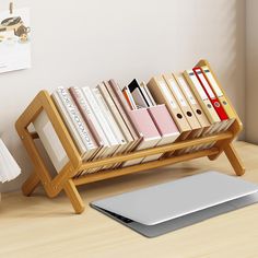 a laptop computer sitting on top of a wooden desk next to a bookshelf