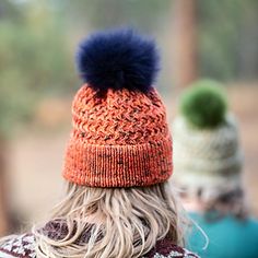 a man with long hair wearing an orange and blue knitted hat, looking off into the distance