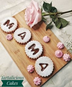 decorated cookies on a cutting board with pink flowers and roses in the background that spell out congratulations cakes