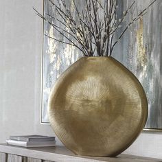 a vase sitting on top of a wooden table next to a painting and a book