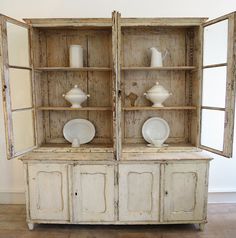 an old china cabinet with two white dishes on it