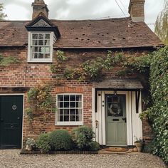 an old brick house with ivy growing on it's walls and door, next to a gravel driveway