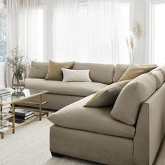 a living room with a couch, coffee table and large windows in the back ground