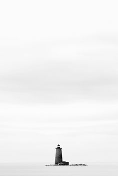 a black and white photo of a lighthouse in the ocean