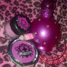 three different types of perfumes on a leopard print tablecloth, one is pink and the other is purple