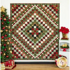 a christmas quilt hanging on the wall next to a christmas tree with presents around it