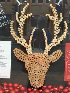 a deer made out of wine corks in front of a window with christmas decorations