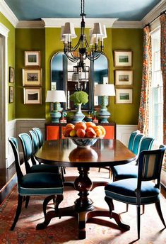 a dining room table with blue chairs and oranges on it in front of a large mirror