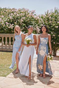 three bridesmaids walking down the aisle with their bouquets in hand and one holding a flower