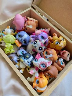 a box filled with little pony toys on top of a white bed sheet in a room