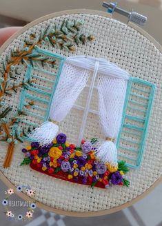 a close up of a embroidery on a piece of cloth with flowers in front of a window