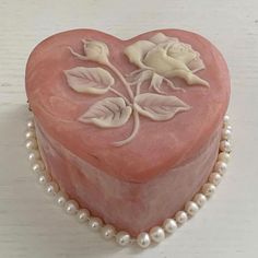 a pink heart shaped box with flowers and pearls