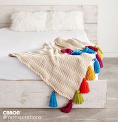 a white bed topped with a blanket covered in multicolored pom poms