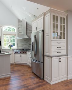 a large kitchen with white cabinets and stainless steel refrigerator freezer combo in the center