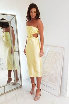 a woman standing in front of a mirror wearing a yellow dress