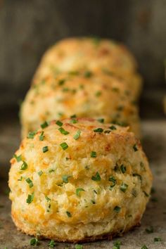 three biscuits with green herbs on them sitting on a baking sheet and ready to be eaten