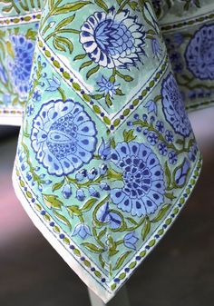 a blue and green flowered tie is hanging on a pole in front of a window