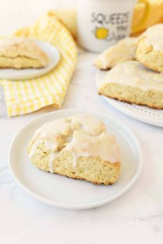 two scones with icing on plates next to a cup of coffee