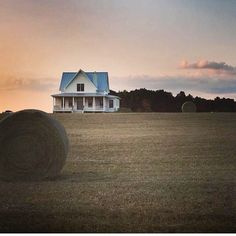 a large hay bale sitting in the middle of a field next to a house