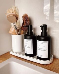 two black bottles are sitting on a shelf next to a brush and soap dispenser