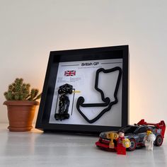 a toy car next to a lego race track set in a shadow box frame on a table