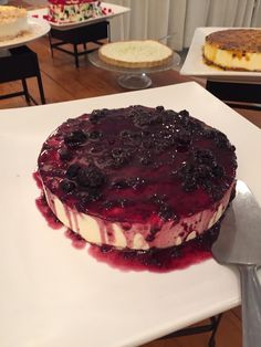 a cake sitting on top of a white plate covered in blueberry toppings next to a knife