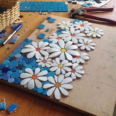 some white and blue flowers sitting on top of a wooden table next to craft supplies