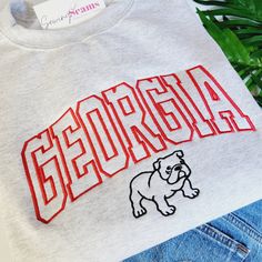 "Experience the perfect blend of style and school spirit with our Georgia Bulldog Crewneck Sweatshirt or T-shirt! Available in three colors, this sweatshirt is designed to keep you cozy and comfortable, whether you're cheering in the stands or just showing off your Bulldog pride around town. At the heart of its design is the iconic \"Georgia\" embroidery, boldly presented across the center chest. The word is intricately stitched in a vibrant red, capturing the essence of the University of Georgi Georgia Bulldogs Shirts Vinyl Men, Collegiate Sweatshirt With Embroidered Graphics, Varsity Sweatshirt With Letter Embroidery For College, College School Spirit Sweatshirt With Embroidered Logo, Collegiate Letter Embroidery Sweatshirt For College, College Sweatshirt With Embroidered Logo For School Spirit, College Sweatshirt With Embroidered Logo, College Sweatshirt With Letter Embroidery For School Spirit, College Sweatshirt With Letter Embroidery