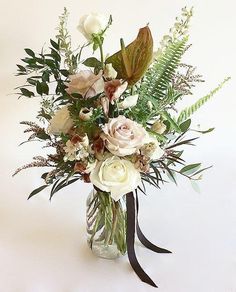 a vase filled with white flowers and greenery