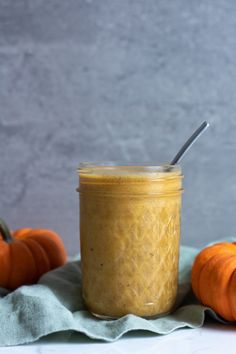 a glass jar filled with peanut butter next to mini pumpkins on a cloth napkin