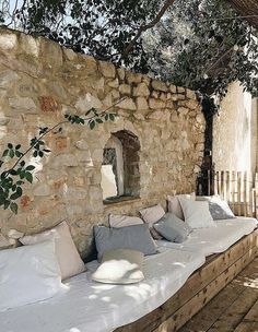 an outdoor seating area made out of pallet wood and stone with pillows on it