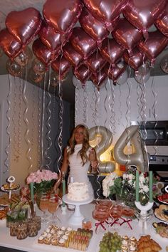 a woman standing in front of a table filled with food and balloons that spell out the number forty