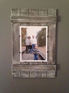 an old wooden frame hanging on the wall with a family photo in it and two people standing next to each other