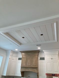 a large kitchen with white cabinets and wood beams on the ceiling, along with an island in the middle