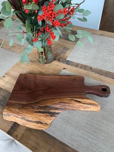 a wooden cutting board sitting on top of a table next to a vase filled with flowers