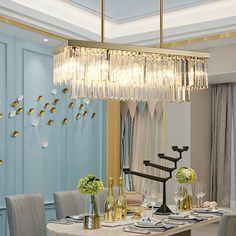 a chandelier hanging over a dining table in a room with blue walls and curtains