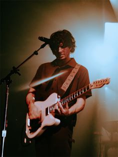 a man playing an electric guitar in front of a microphone