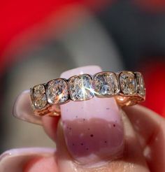 a woman's hand holding a gold ring with three different sized diamonds on it