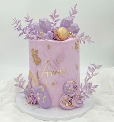 a pink cake with purple flowers and gold decorations