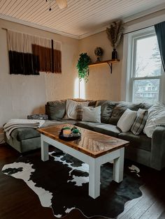 a living room with a couch, coffee table and cow hide rug on the floor