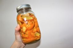 a person holding a jar full of food in front of a white wall with the lid open