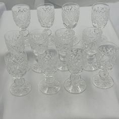 an assortment of crystal goblets sitting on a white tablecloth covered table cloth